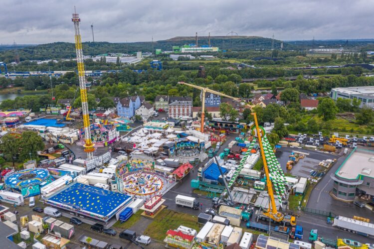 Die Luftbildaufnahme des Kirmesplatzes (Bild re.) zeigt den Fortschritt des Aufbaus am Donnerstag-nachmittag, 27.07.2023
