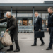 Finanzamt bittet Flaschensammler:innen zur Kasse – was wirklich gilt Ein älterer, wettergegerbter Mann sammelt Flaschen aus einem Mülleimer vor einem Aldi-Supermarkt, während sich ein Finanzbeamter und ein Polizist nähern.