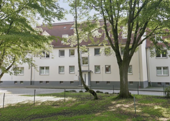 Heizungsausfall am Hülsmanns Hof in Herne: Mieter:innen der LiLa Domus GmbH zwischen Kälte und Fragen Helles Wohngebäude zwischen Bäumen im Hüllsmanns Hof in Herne.