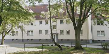 Helles Wohngebäude zwischen Bäumen im Hüllsmanns Hof in Herne.