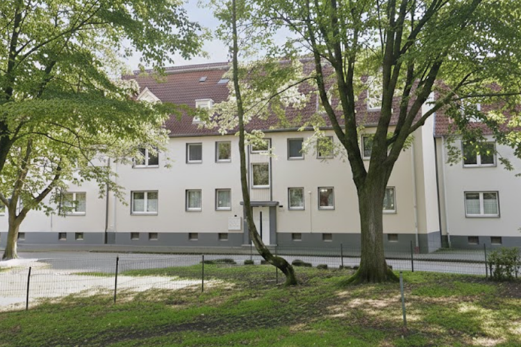 Helles Wohngebäude zwischen Bäumen im Hüllsmanns Hof in Herne.