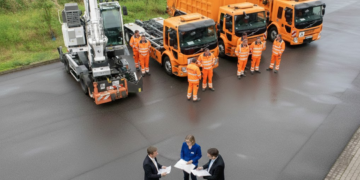 Besprechung vor orangefarbenen Müllfahrzeugen.