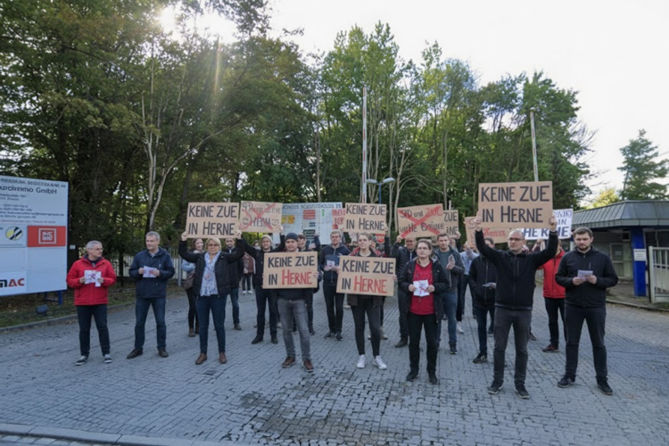 Demonstrierende halten Schilder mit der Aufschrift „KEINE ZUE IN HERNE“ bei einer Kundgebung im Freien.