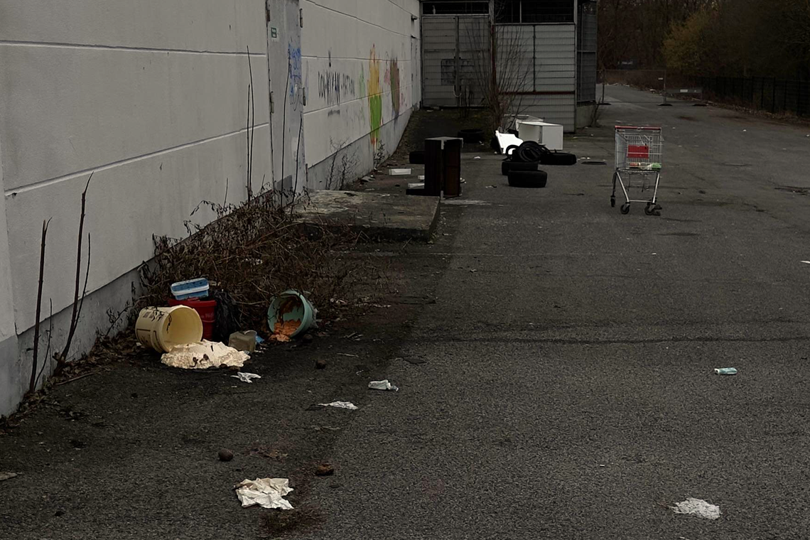 Vermüllter Parkplatz mit Abfall und Einkaufswagen.