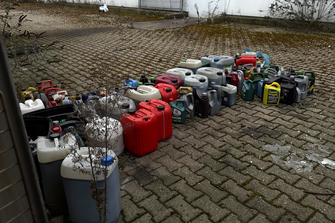 Reihe von Altöl-Kanistern auf dem Boden.