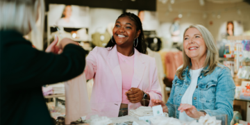 Glückliche Kundinnen genießen die persönliche Beratung beim Shoppen von hochwertiger Mode.
