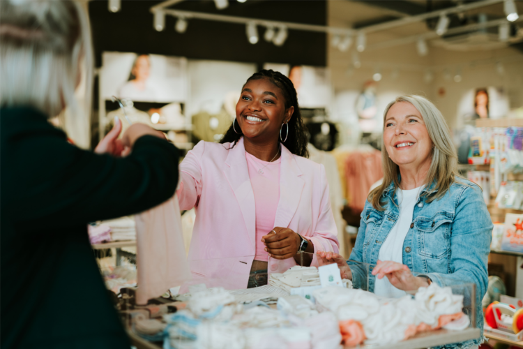 Glückliche Kundinnen genießen die persönliche Beratung beim Shoppen von hochwertiger Mode.