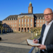 Stefan Budde-Siegel, Herausgeber und Chefredakteur der SN Sonntagsnachrichten, notiert Gedanken im Vordergrund vor der markanten, historischen Fassade des Herner Rathauses auf dem Rathausplatz in Herne.