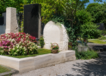Gepflegte Grabstätte von Ida Krottendorf auf einem Friedhof mit Blumen, Steinmalen, Kiesweg und viel Grün bei Tageslicht.