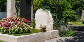 Gepflegte Grabstätte von Ida Krottendorf auf einem Friedhof mit Blumen, Steinmalen, Kiesweg und viel Grün bei Tageslicht.