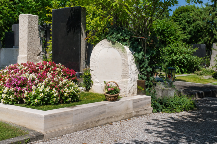 Gepflegte Grabstätte von Ida Krottendorf auf einem Friedhof mit Blumen, Steinmalen, Kiesweg und viel Grün bei Tageslicht.