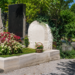 Gepflegte Grabstätte von Ida Krottendorf auf einem Friedhof mit Blumen, Steinmalen, Kiesweg und viel Grün bei Tageslicht.