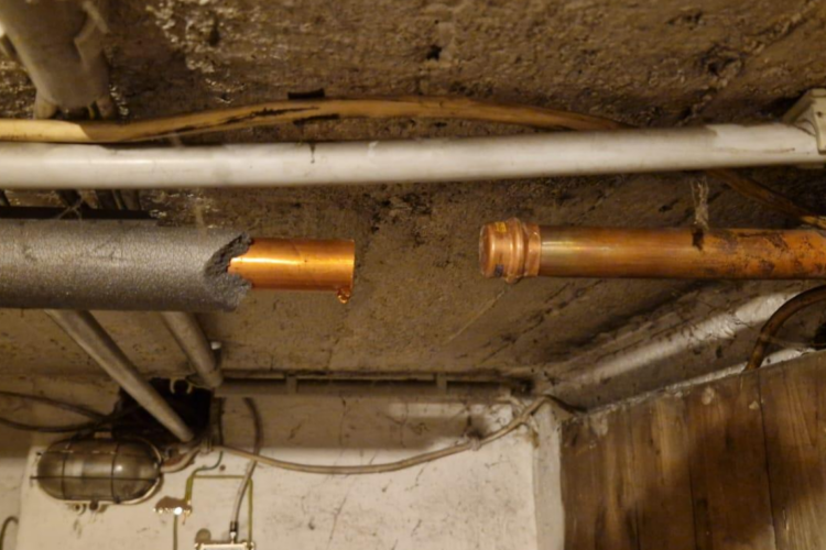 Offen getrennte Kupferrohrleitung unter einer Kellerdecke mit Dämmung, Leitungen, Kabeln und sichtbaren Verschmutzungen im Deckenbereich. In der Wiescherstraße 16 in Herne.