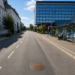 Straßenszene am Friedrich-Ebert-Platz in Herne mit Bushaltestelle, Sparkassen-Hochhaus und Bronzeplatte „Mitte von Herne“ auf der Fahrbahn.