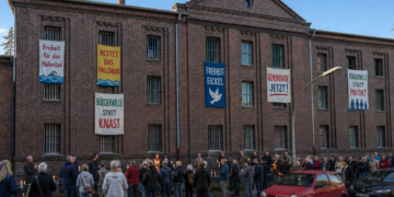 Mahnwache vor ehemaligem Gefängnisgebäude in Eickel mit bunten Bannern an vergitterten Fenstern für Hallenbad, Freiheit und Bürgerwillen.