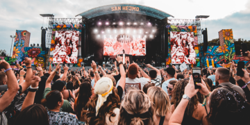 Besucher:innen vor der farbenfrohen Mainstage des San Hejmo Festivals am Airport Weeze während eines Liveauftritts.