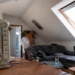 Hitze im Dachgeschoss: Wann fehlende Dämmung zum Mangel wird Innenansicht einer aufgeheizten Dachgeschosswohnung mit Dachschrägen, Thermometer ohne lesbare Werte und starkem Sonnenlichteinfall.