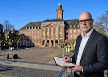 Stefan Budde-Siegel, Herausgeber und Chefredakteur der SN Sonntagsnachrichten, notiert Gedanken im Vordergrund vor der markanten, historischen Fassade des Herner Rathauses auf dem Rathausplatz in Herne.