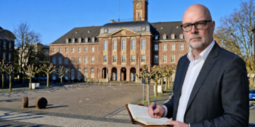 Stefan Budde-Siegel, Herausgeber und Chefredakteur der SN Sonntagsnachrichten, notiert Gedanken im Vordergrund vor der markanten, historischen Fassade des Herner Rathauses auf dem Rathausplatz in Herne.