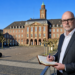 Stefan Budde-Siegel, Herausgeber und Chefredakteur der SN Sonntagsnachrichten, notiert Gedanken im Vordergrund vor der markanten, historischen Fassade des Herner Rathauses auf dem Rathausplatz in Herne.