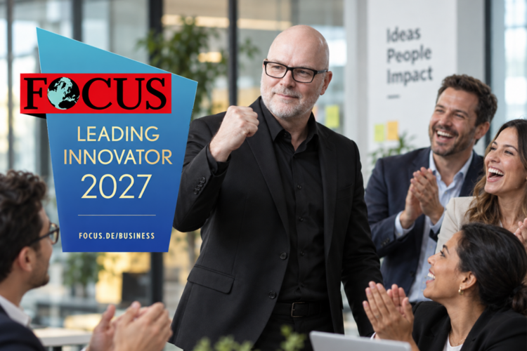 Mann im schwarzen Anzug und mit Brille steht in einem modernen Büro vor applaudierenden Kolleg:innen und hebt die Faust. Links ist das Logo „FOCUS Leading Innovator 2027“ eingeblendet.