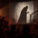 Zwei Musiker begleiten eine Stummfilmprojektion mit einer Vampirgestalt vor Publikum.