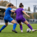 SGS Essen empfängt den VfL Bochum zum Revierduell Zwei Fußballerinnen in blauen und violetten Trikots kämpfen auf einem Fußballplatz um den Ball.