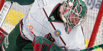 Torhüter Dieter Geidl in weiß-grüner Ausrüstung vor dem Eishockeytor.