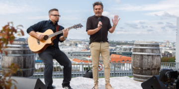 Thomas Anders mit Mikrofon und ein Gitarrist auf einer Dachterrasse.